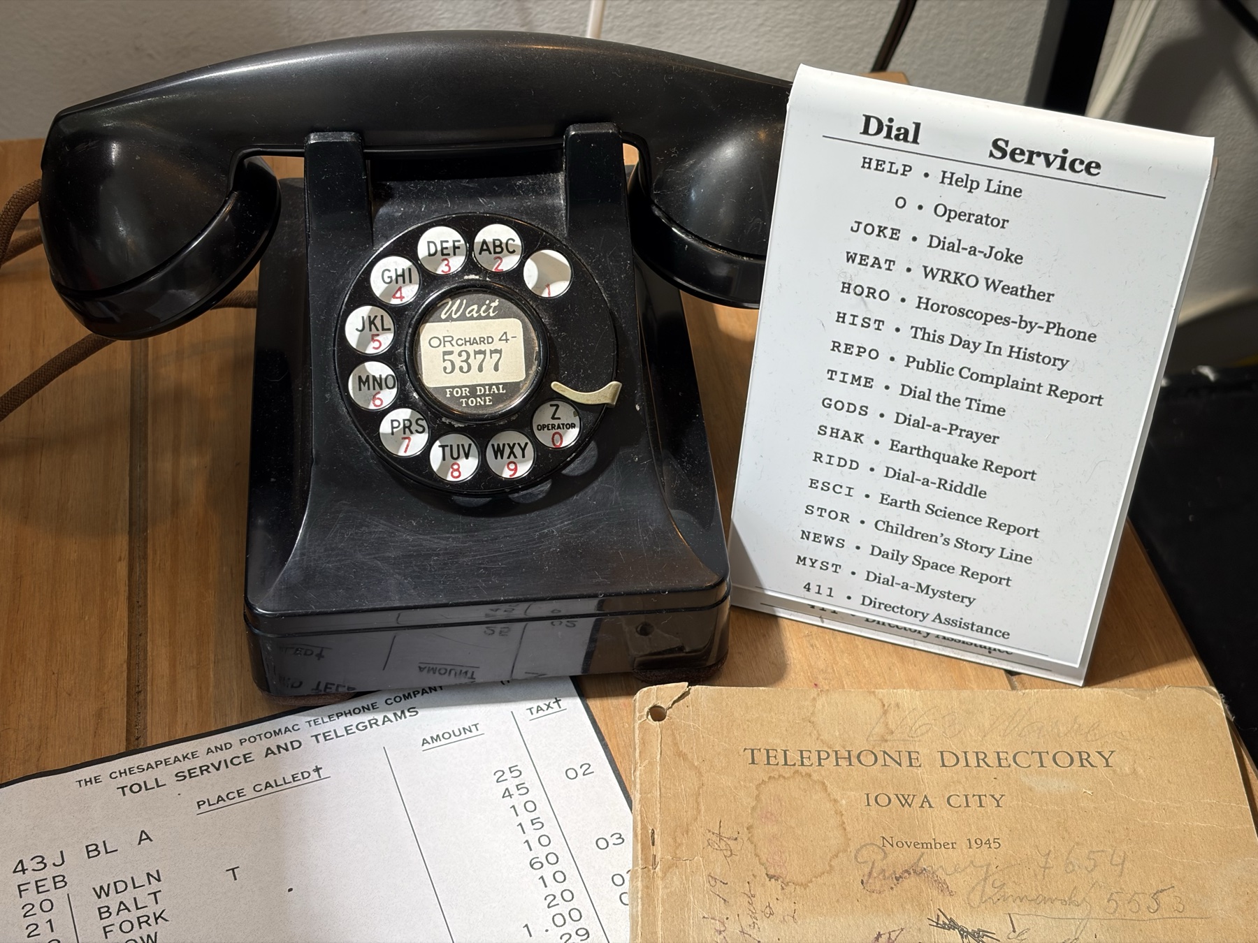 A real vintage telephone next to a printed Dial / Service card listing POTSBox extensions